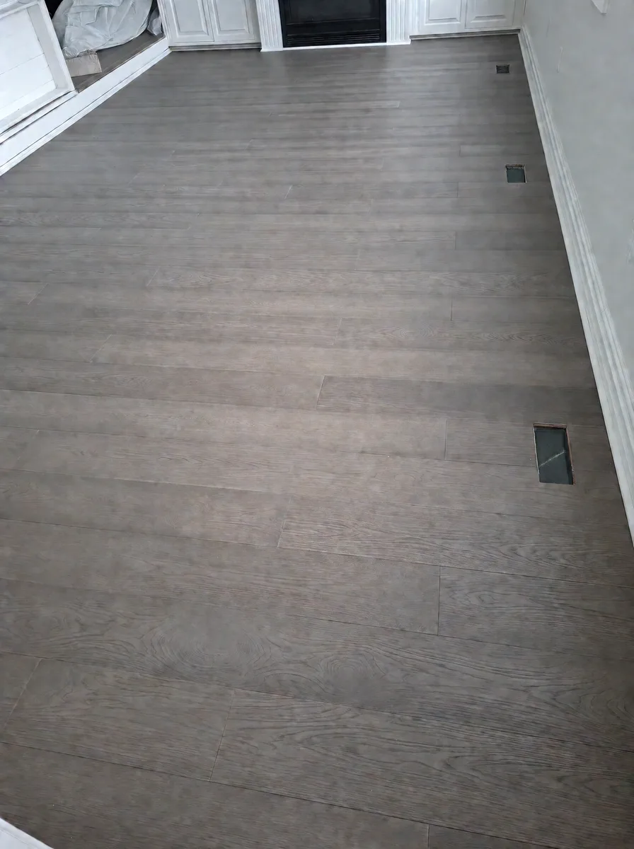 New grey-brown wide-plank oak floor running toward the fireplace built-ins