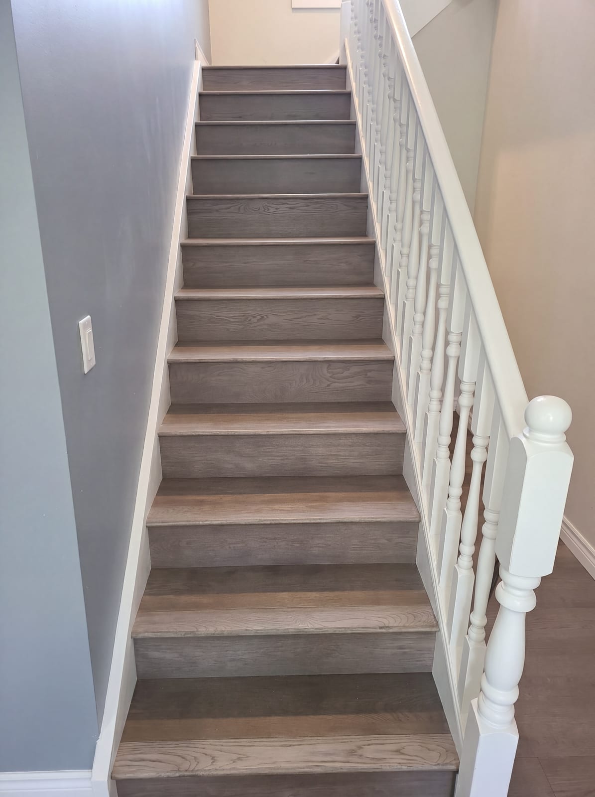 Refinished wood staircase with white railing after the stair replacement