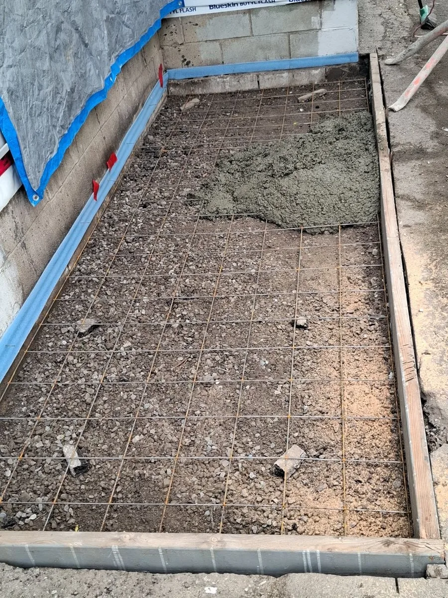 Side deck build with grey decking and white railing — concrete base prep