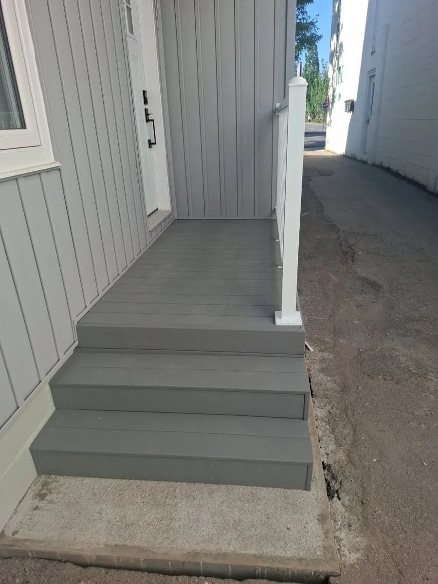 Side deck build with grey decking and white railing — finished entry steps