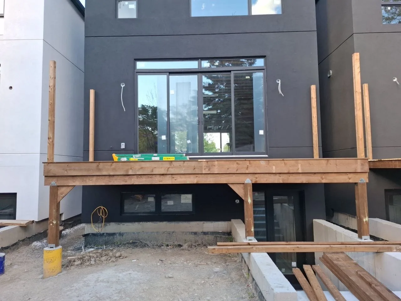 Modern Toronto townhome deck build with natural wood decking and railing — ledger and beam installed