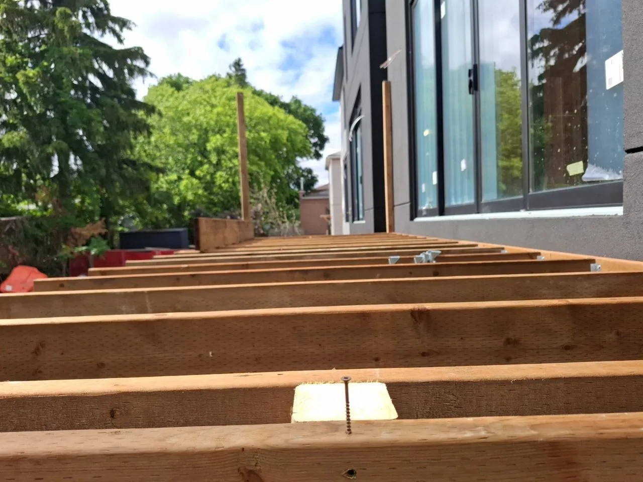 Modern Toronto townhome deck build with natural wood decking and railing — floor joists installed